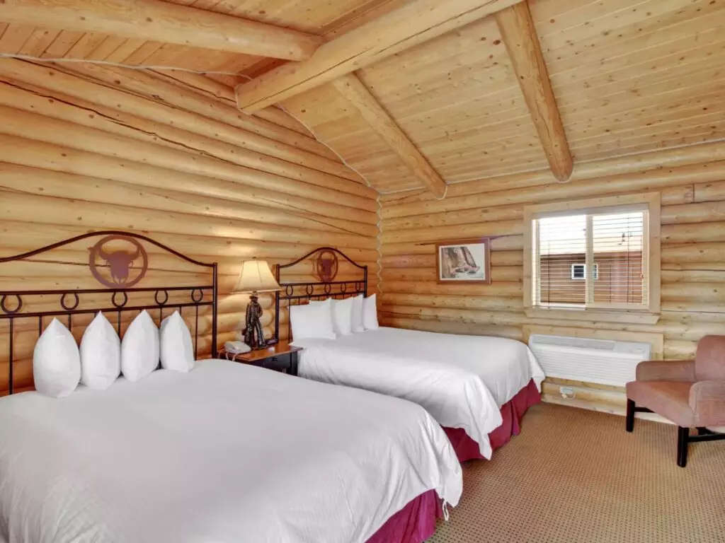 A Log Cabin Bedroom With Two Full-Sized Beds